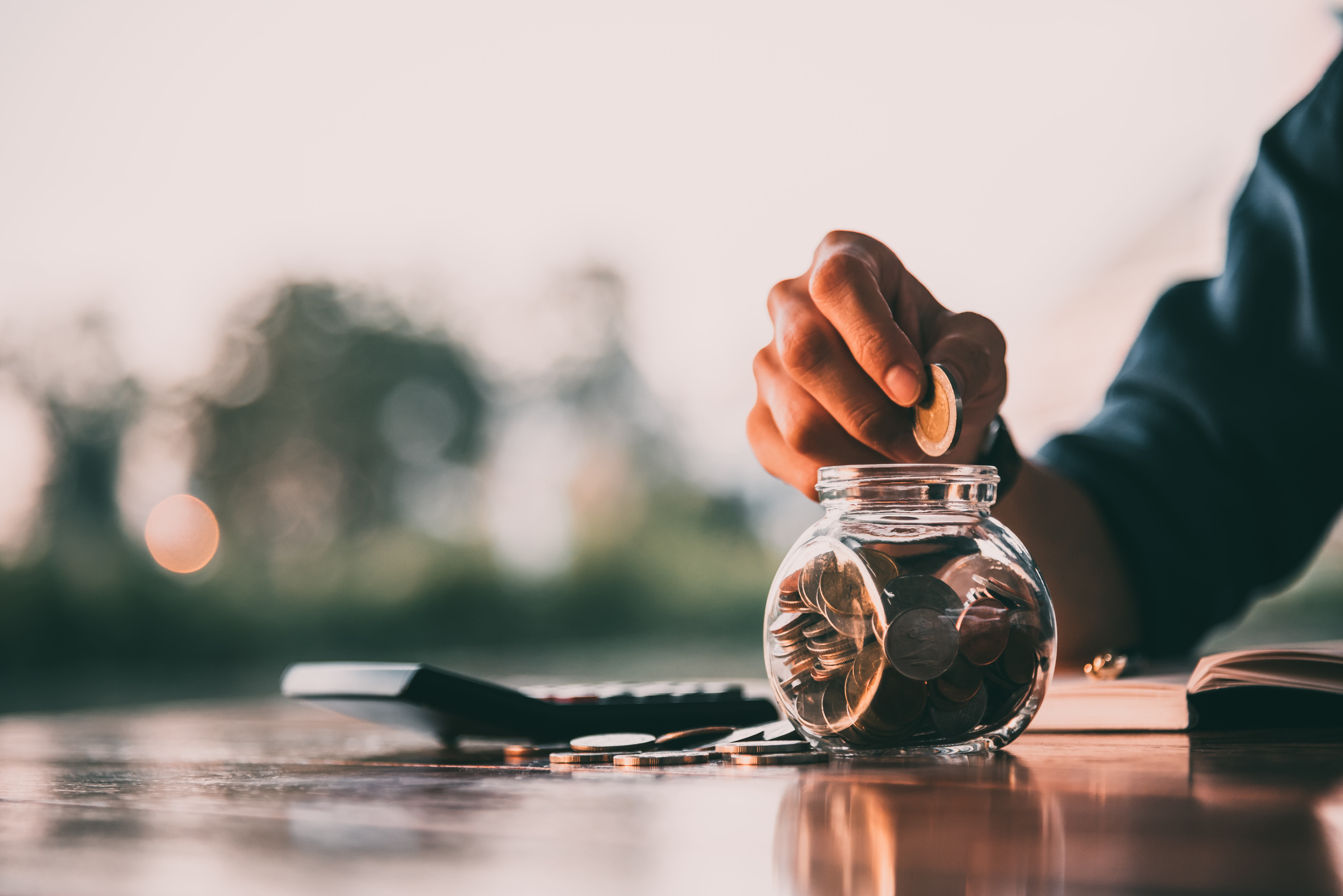 person putting coins in a jar