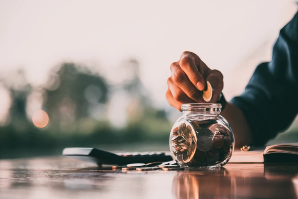 person putting coins in a jar