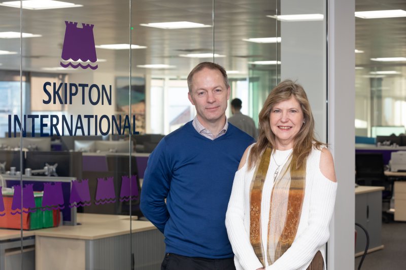 people smiling in front of Skipton logo