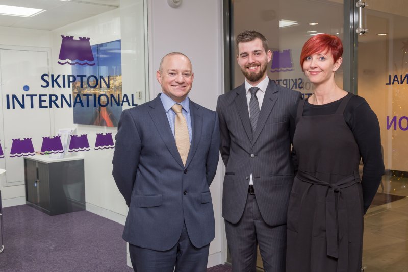 people smiling in front of Skipton logo