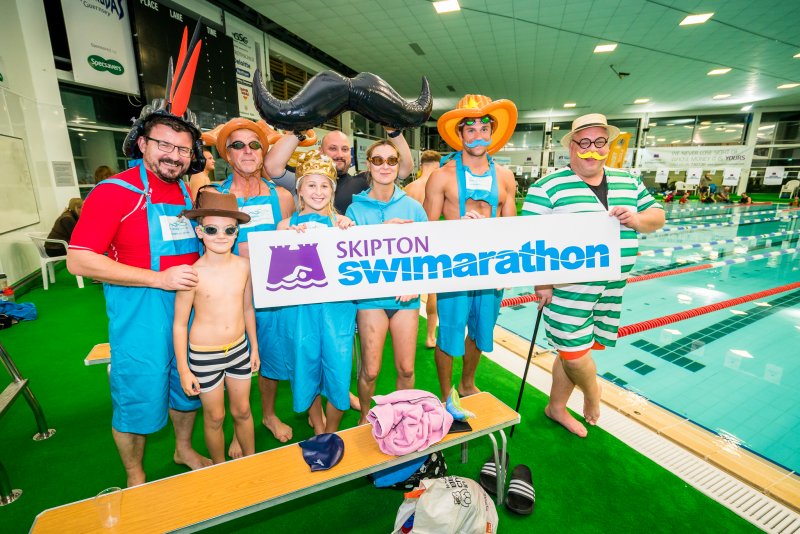 People dressed up holding Swimarathon sign