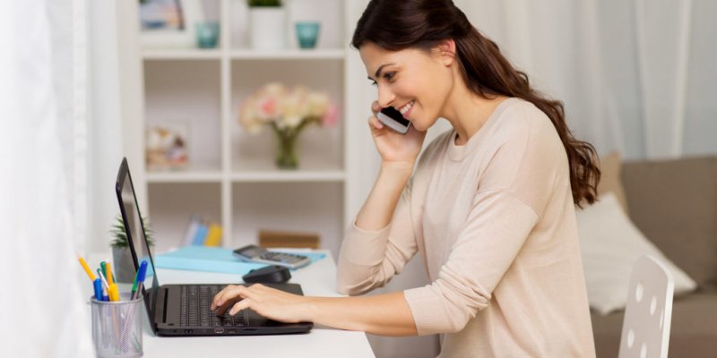 women smiling on the phone looking at computer