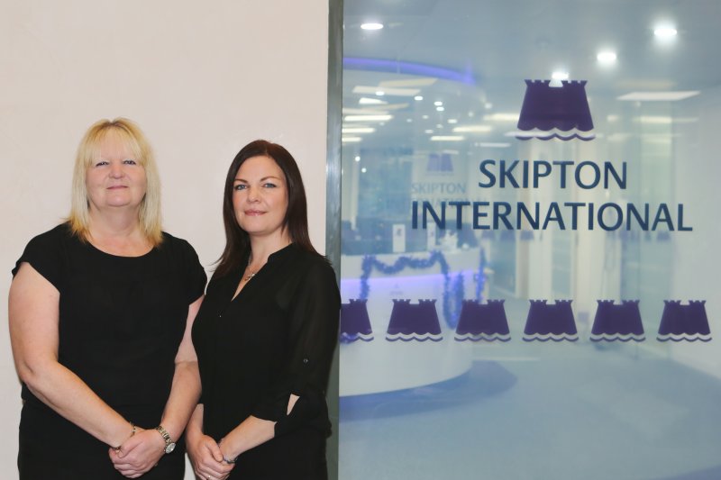 two women smiling Infront of Skipton International logo