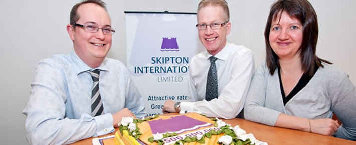 3 people sat on a tble with a cake