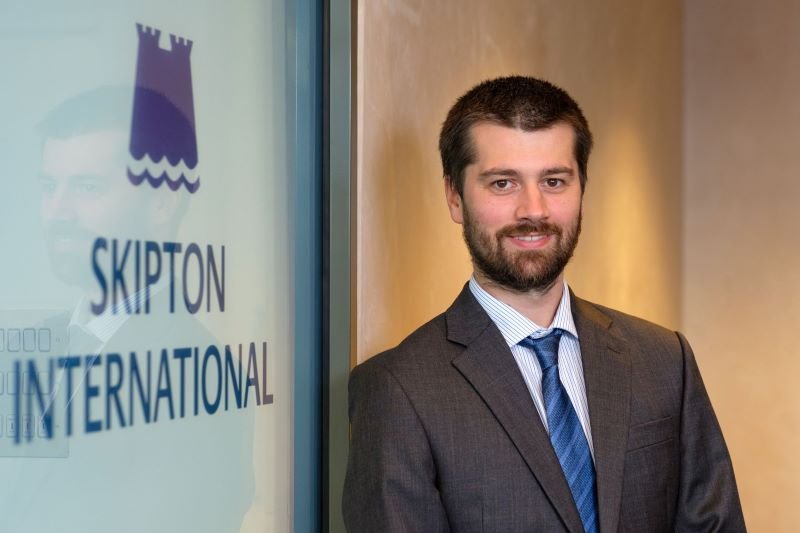 man smiling next to Skipton logo