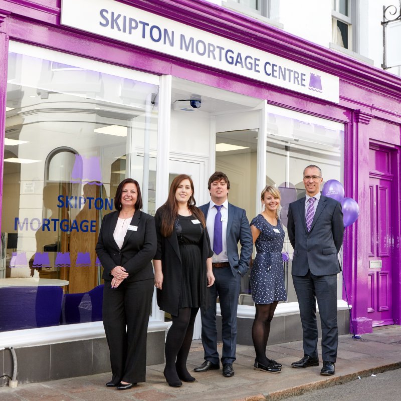people smiling in front of Skipton logo